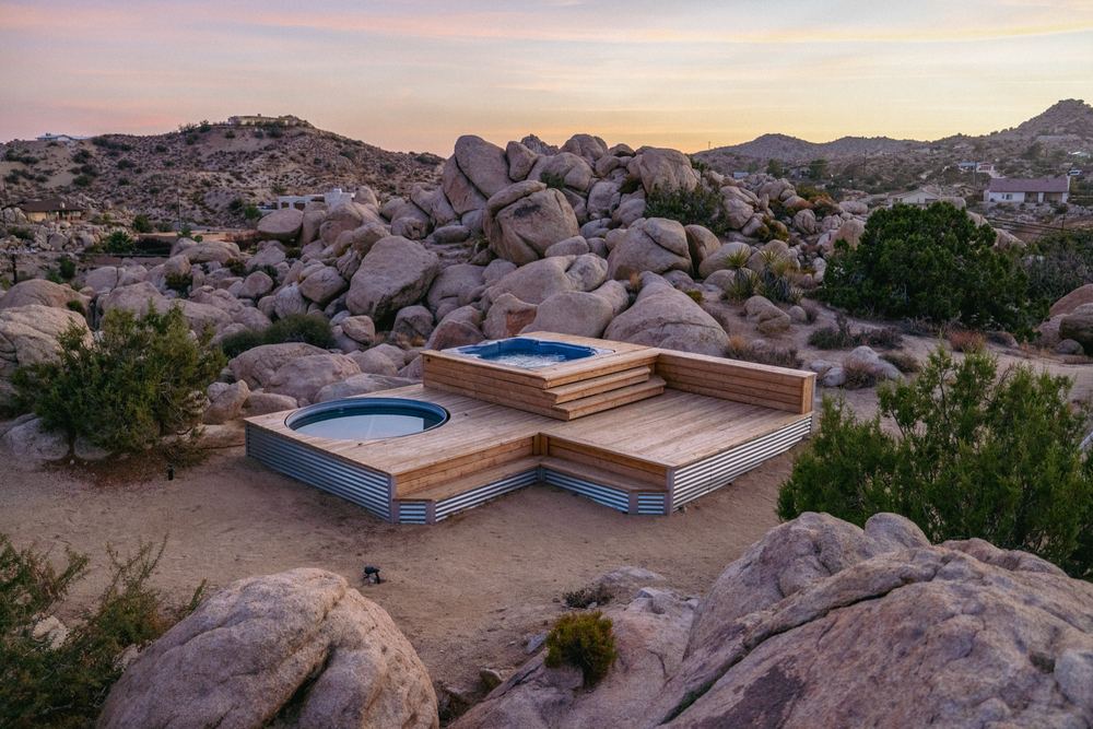 A hot tub set into the boulders at one of our high-desert houses, at dusk